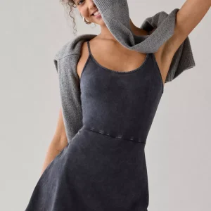 Woman wearing dark charcoal knit fit-and-flare romper with sweater draped over shoulders