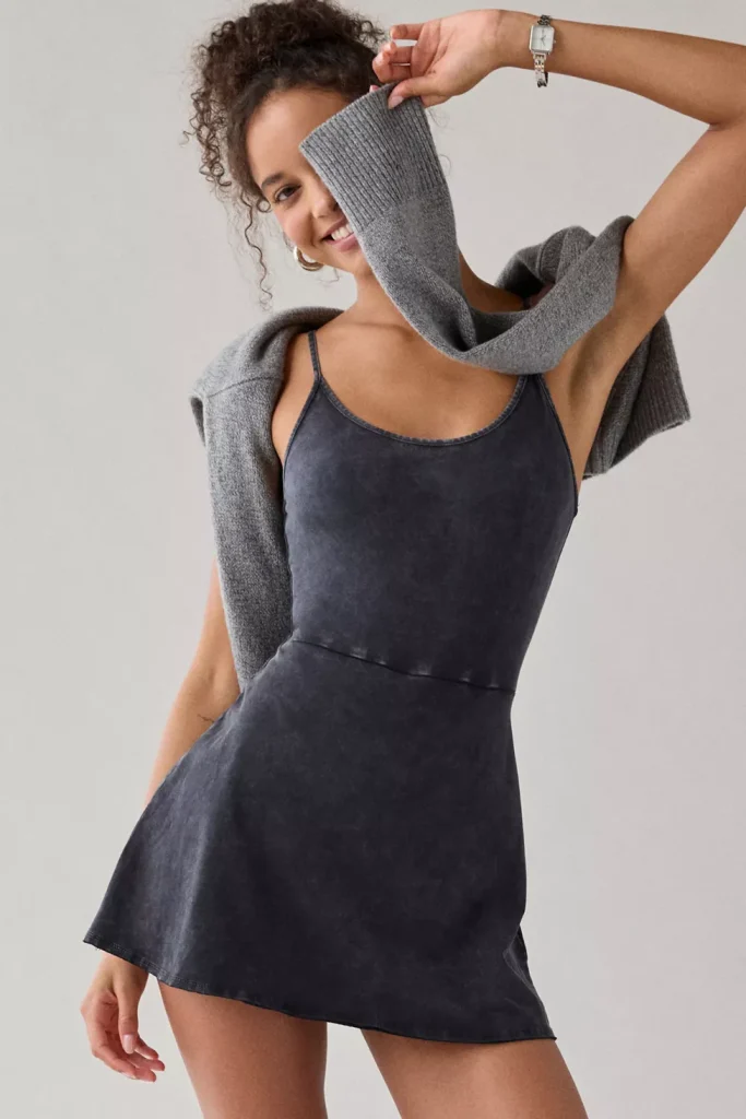 Woman wearing dark charcoal knit fit-and-flare romper with sweater draped over shoulders