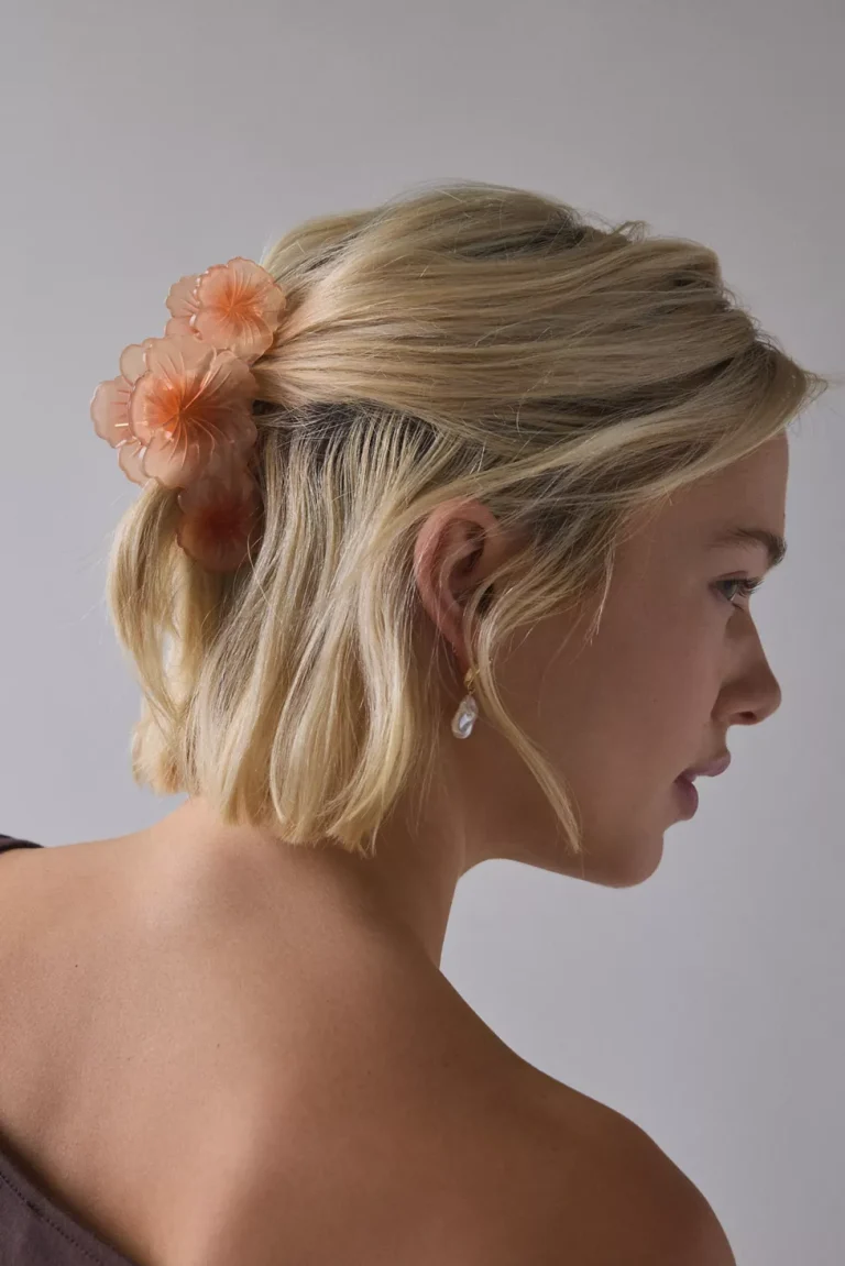 Woman with blonde hair wearing peach hibiscus floral claw clip