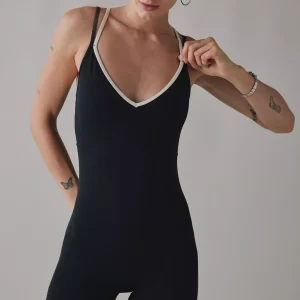 Woman wearing black unitard romper with white V-neck trim