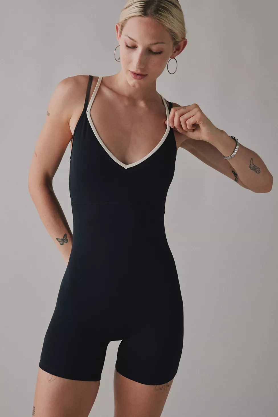Woman wearing black unitard romper with white V-neck trim